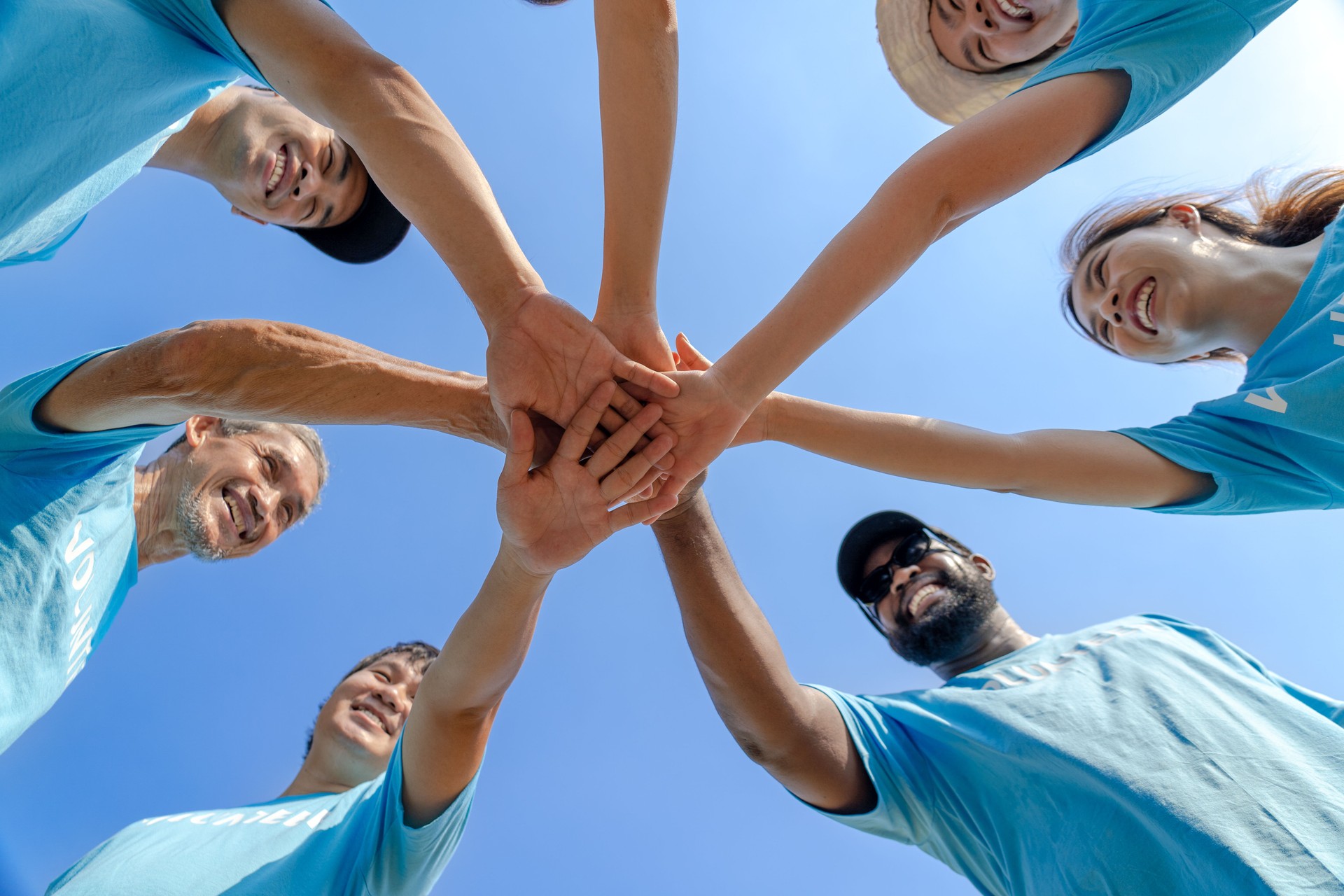 Group of happy diverse volunteers joining stacked hands together